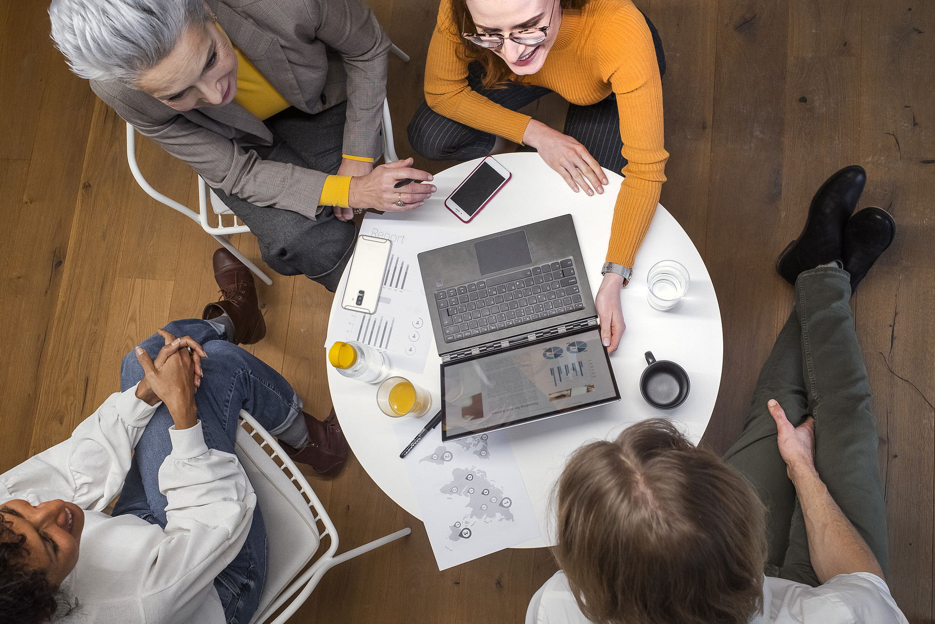Vier Personen sitzen um einen Tisch und arbeiten an Laptops und Papieren.